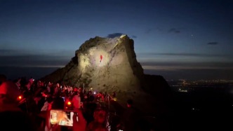 男子擎国旗登山，众多游客用手电筒为他照亮山路