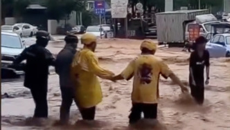 雨天骑车人摔倒在洪流中，几名外卖员手牵手蹚水施救