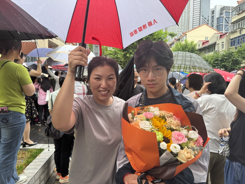 家长细雨中手捧鲜花等待，上海考生希望“外语二刷考到更理想的分数”