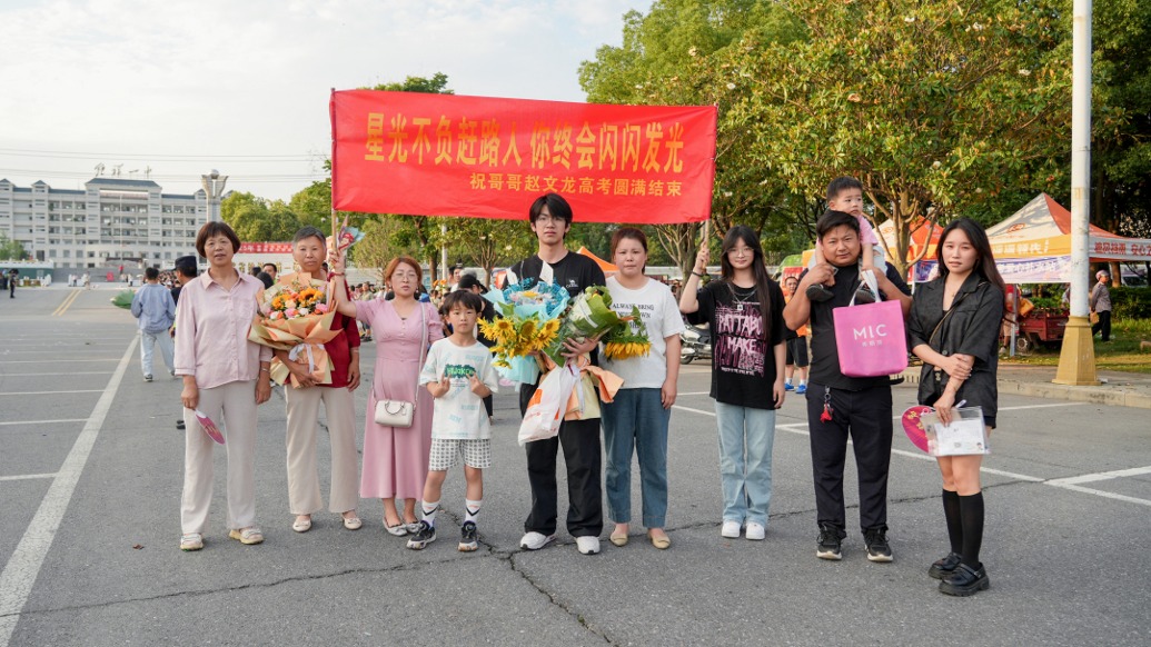 高考最后一場結(jié)束，一考生一家九口人到場打橫幅祝賀