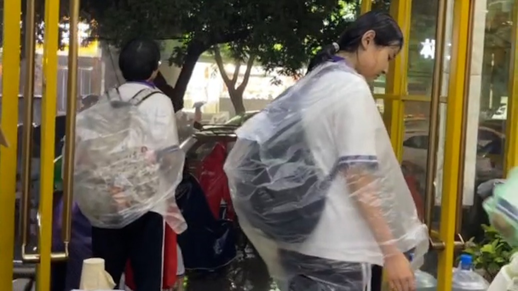 放学遇大雨,宠物店主邀请学生进店躲雨还为他们做“雨衣”