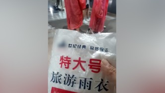 北京遭遇强降雨天气，地铁站工作人员为乘客免费发雨衣