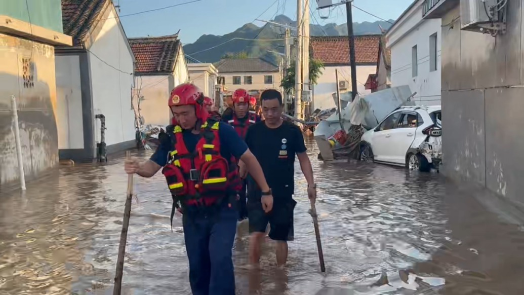 北京密云洪水過(guò)后消防人員排查井蓋，喊話回家村民：“我走前面，你跟著走”