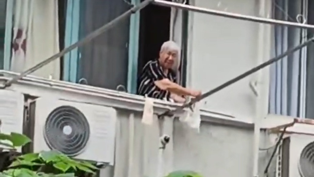 看見工人酷暑天干活，老人用長桿為他們“空投”冰淇淋