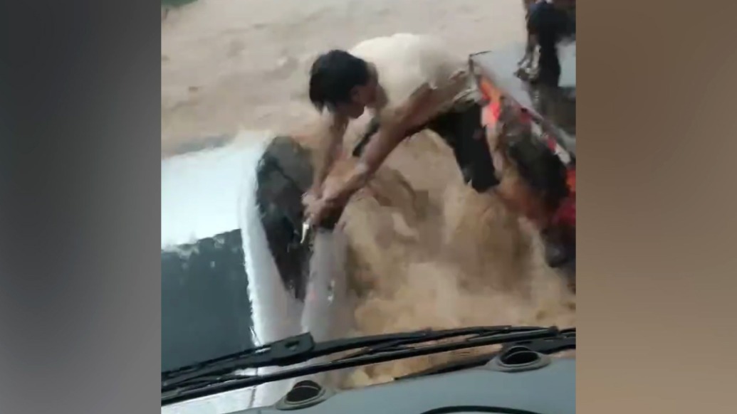 私家车被洪水围困，男子脚跨激流抡锤砸窗救人