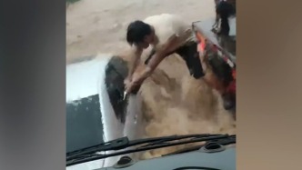 私家车被洪水围困，男子脚跨激流抡锤砸窗救人