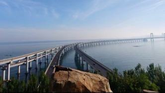 大连一跨海大桥观景台有游客翻栏杆踩空心造景石拍照，当地回应