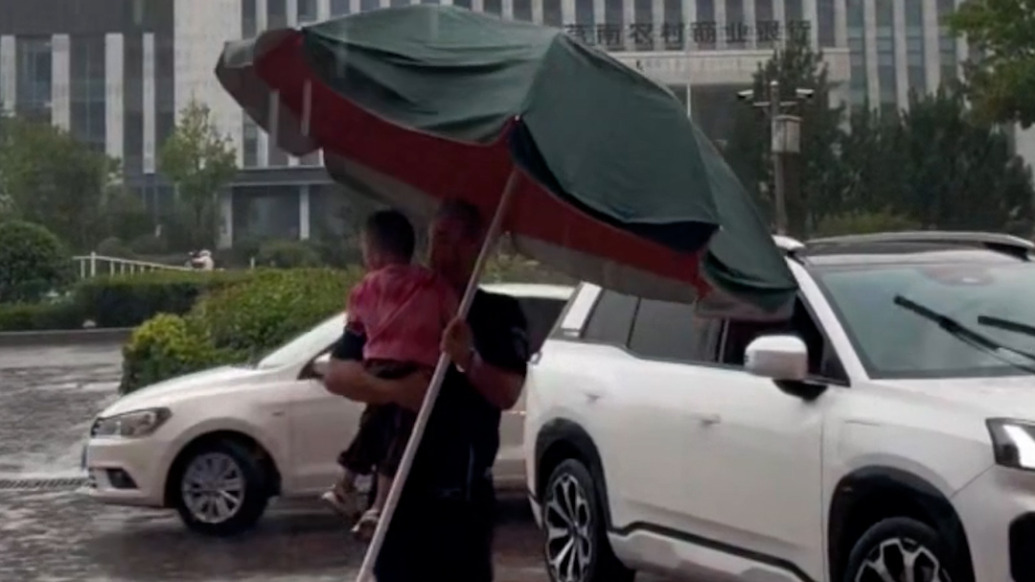 突降大雨,幼儿园保安爷爷扛太阳伞挨个“摆渡”孩子入园