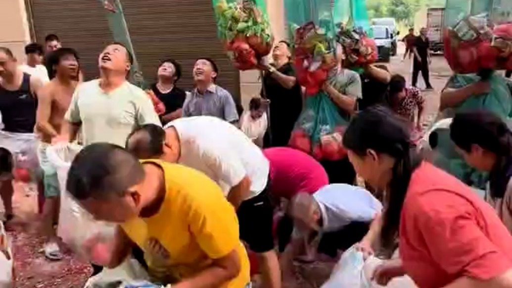 主人喬遷新居站樓頂拋撒紅包、零食，街坊舉網(wǎng)兜接喜氣