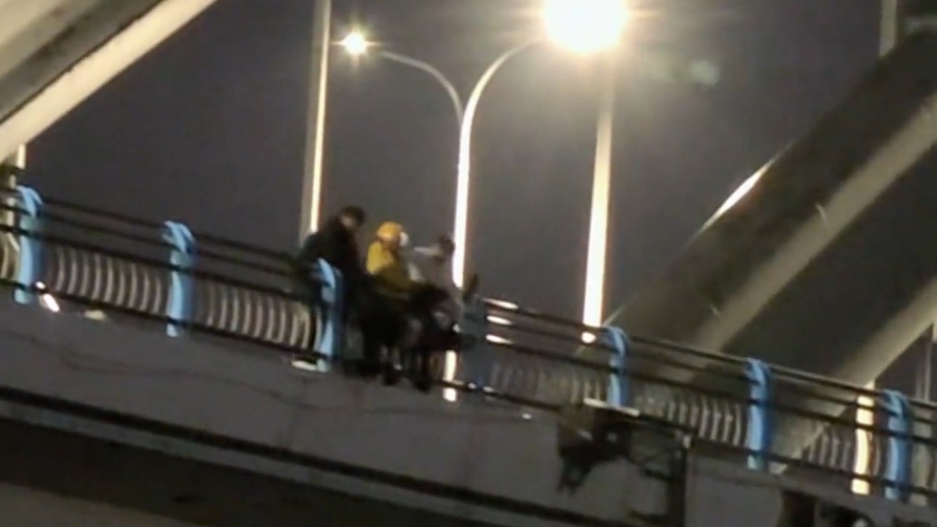 男子翻越护栏欲跳桥，4名路人紧紧把他拽住