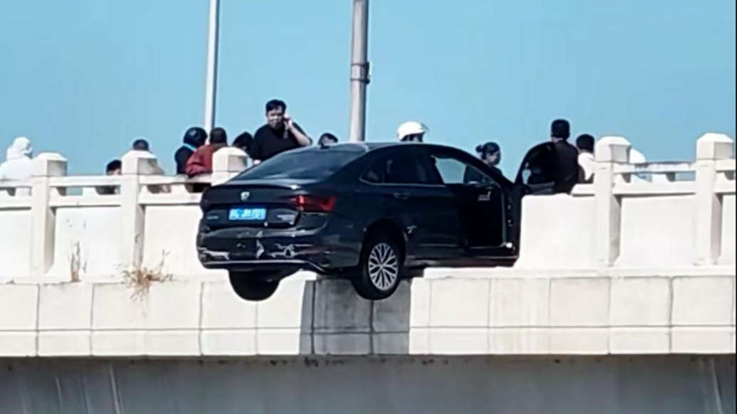 轎車撞斷盧溝新橋護(hù)欄車身半懸空中，房產(chǎn)中介一手壓車頭施救一手撥電話報(bào)警