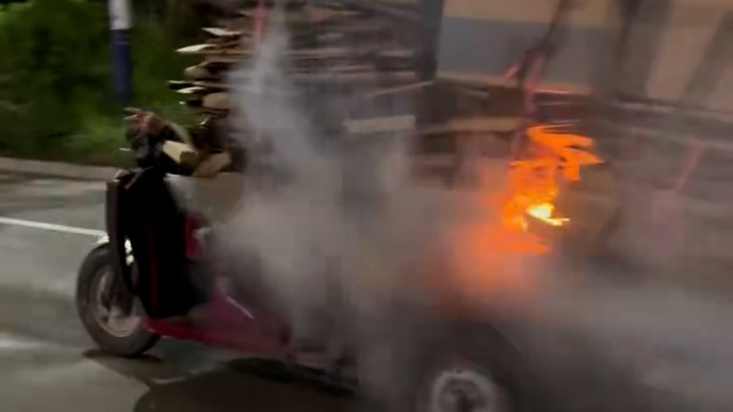 大爺邊抽煙邊騎三輪車所載紙板著火，路人及時提醒