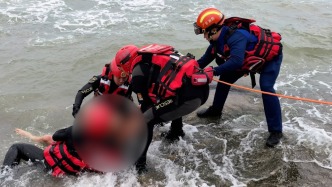 游客在海邊撿小螃蟹遇漲潮被困礁石，消防員涉水救人 