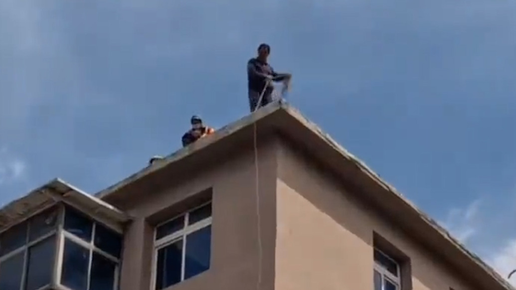 住户陪工人上楼顶干活恐高不敢下来，求助消防后被云梯稳稳接下