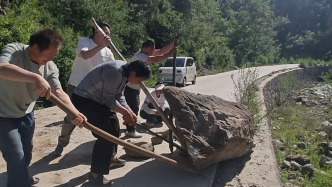 齐心协力！大石头横挡路面阻碍交通，村民村干部拿来木棍合力挪移