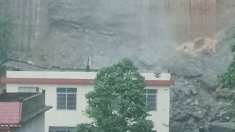 受强降雨影响广西东兰县一处民房后侧边坡滑坡，1人被困2人受伤救援正进行