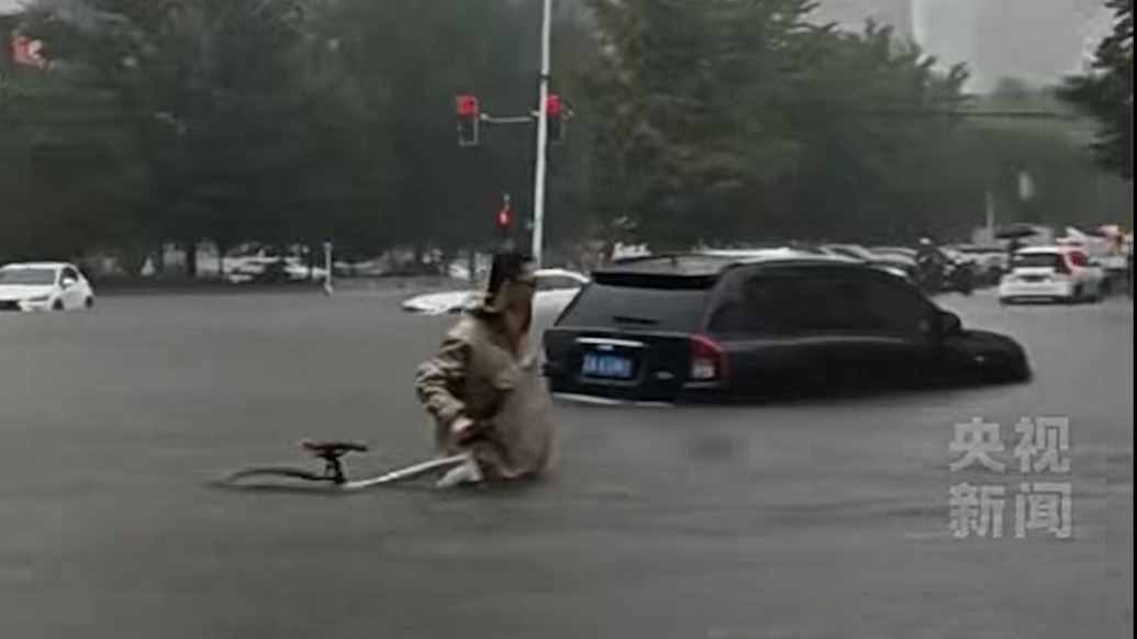 男子推自行车蹚齐腰深积水去上班:这班真是非去不可,因为我是产科医生