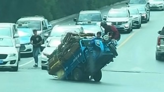 “搭把手的事”，三轮车在道路中央突然“翘头”，路人纷纷上前合力扶正
