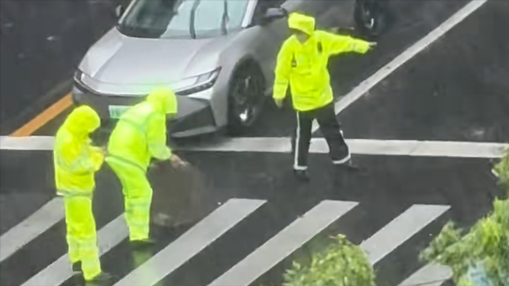暴雨后上海一路面出现危险敞开井口，他们冒雨将窨井盖及时复位