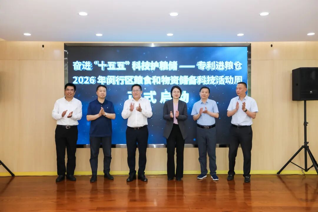 2026年闵行区粮食和物资储备科技活动周正式启动现场,多位嘉宾在活动主题大屏前合影